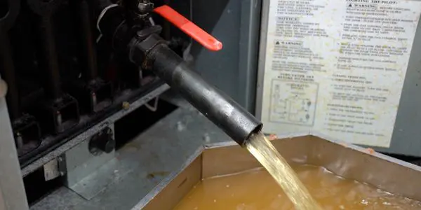 Water draining from a pipe into container.