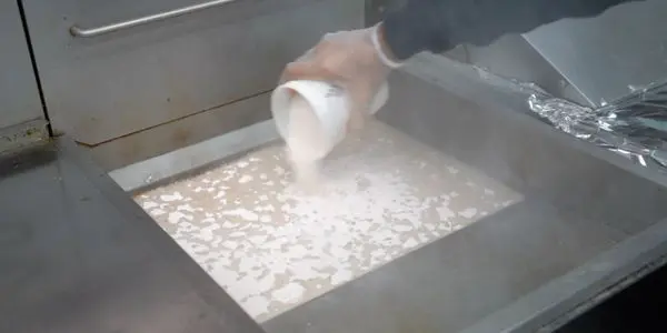 Pouring liquid onto a hot griddle surface.