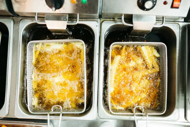 French fries frying in deep fryers.